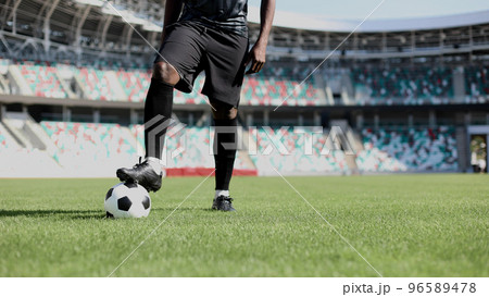 African American man playing football on the stadium field. A man runs with a soccer ball across the field. African American man playing football on the stadium field. A man runs with a soccer ball across the field. 96589478