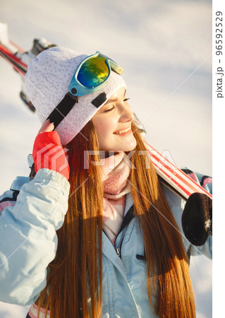 Sunny weather in mountains. Girl with skis on her shoulders. Skiing in winter. Sunny weather in mountains. Girl with skis on her shoulders. Skiing in winter. 96592529
