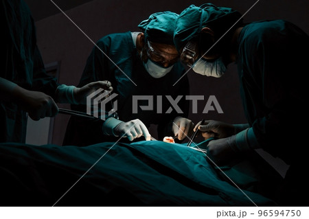 Surgical team performing surgery to patient in sterile operating room. Surgical team performing surgery to patient in sterile operating room. 96594750