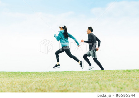 公園をスピードを出してダッシュでランニングするスポーツウェアを着たアジア人男女の後ろ姿 96595544