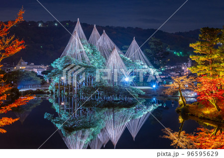 晩秋の紅葉と冬の風物詩雪吊りが兼六園の霞ヶ池に美しく反射する夜景｜石川県金沢市 96595629