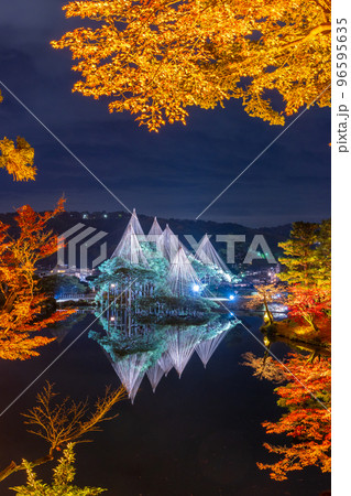 晩秋の紅葉と冬の風物詩雪吊りが兼六園の霞ヶ池に美しく反射する夜景｜石川県金沢市 96595635