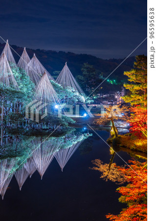 晩秋の紅葉と冬の風物詩雪吊りが兼六園の霞ヶ池に美しく反射する夜景｜石川県金沢市 96595638
