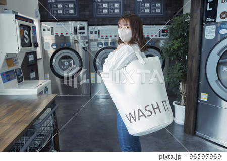 コインランドリーでランドリーバッグを持つ若い女性 コインランドリーでランドリーバッグを持つ若い女性 96597969