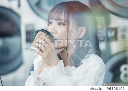 コインランドリーでお茶をする若い女性 コインランドリーでお茶をする若い女性 96598101