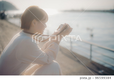 ミラーレスカメラを持った若い女性の写真 96599384