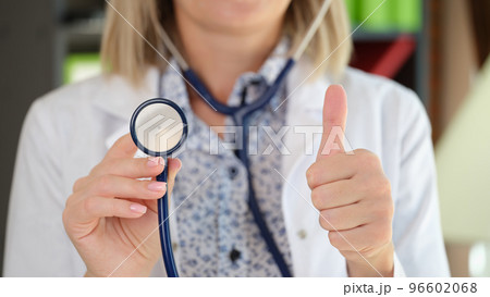 Woman practitioner posing in clinic office showing stethoscope and thumb up gesture Woman practitioner posing in clinic office showing stethoscope and thumb up gesture 96602068