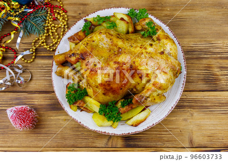 Baked whole chicken with potato and Christmas decorations on a wooden table. Top view 96603733
