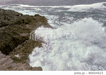 Waves breaking on the rocks at the shore of the beach 96604825