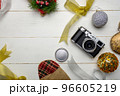 Flat lay festive composition with photo camera and colorful Christmas decorations on white wooden background with space for text 96605219