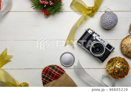 Flat lay festive composition with photo camera and colorful Christmas decorations on white wooden background with space for text 96605219