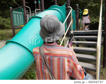 公園で孫の遊びを見守る祖母の後ろ姿 96606797