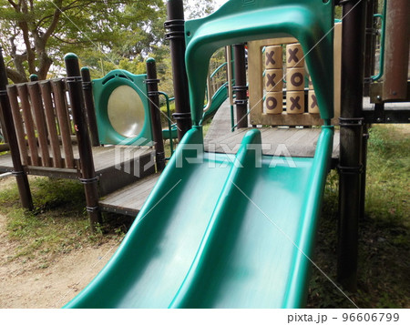 公園の広場に設置された緑色のすべり台がある子供用複合遊具 96606799
