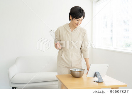 タブレットを見ながら料理をする女性 タブレットを見ながら料理をする女性 96607327