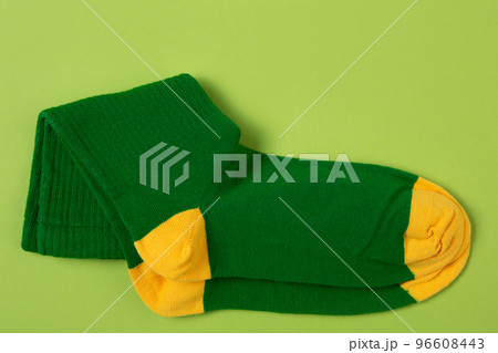 A pair of green socks with yellow toes and heels, on a green background 96608443