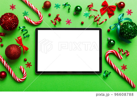 Top view of empty tablet on Christmas background made of new year decorand festive decorations. New year holiday concept. Mockup Top view of empty tablet on Christmas background made of new year decorand festive decorations. New year holiday concept. Mockup 96608788