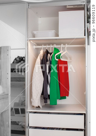 Clothes hang on a hanger in the closet. 96609119