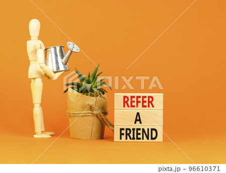 Refer a friend symbol. Concept words Refer a friend on wooden blocks on a beautiful orange table orange background. Businessman model. Business and refer a friend concept. Copy space. 96610371