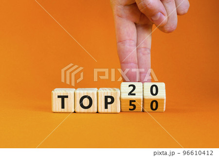 From Top 50 to 20 symbol. Businessman turns wooden cubes and changes concept words Top 50 to Top 20. Beautiful orange table orange background. Business and from Top 50 to Top 20 concept. Copy space. 96610412