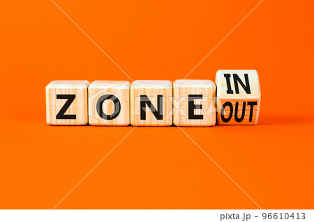 Zone in or out symbol. Concept words Zone in and Zone out on wooden cubes. Beautiful orange table orange background. Business zone in or out concept. Copy space. 96610413