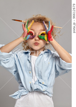 Beautiful little girl with a painted hands is posing on a gray background. Beautiful little girl with a painted hands is posing on a gray background. 96612679