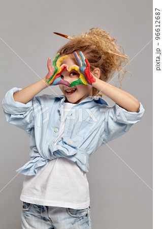 Beautiful little girl with a painted hands is posing on a gray background. Beautiful little girl with a painted hands is posing on a gray background. 96612687