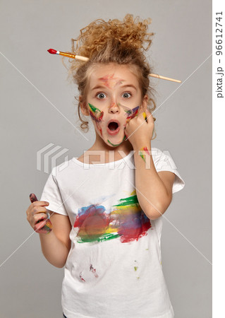 Beautiful little girl with a painted fingers is posing on a gray background. Beautiful little girl with a painted fingers is posing on a gray background. 96612741