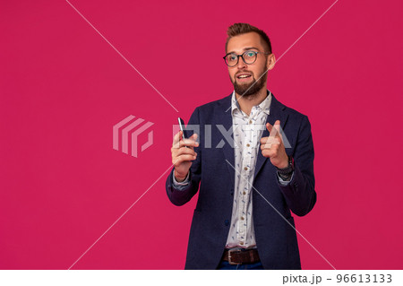 Studio shot of attractive brunette business man with glasses, in casual shirt, stylish black jacket holding a smartphone and smiling. Studio shot of attractive brunette business man with glasses, in casual shirt, stylish black jacket holding a smartphone and smiling. 96613133