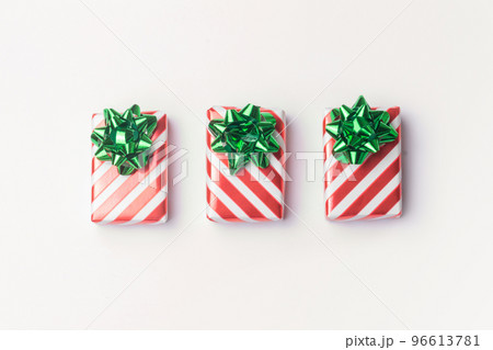 Christmas presents and new year gifts in red striped wrapping paper with green bows on white background with copy space. 96613781
