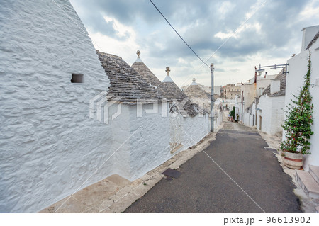 Beautiful town of Alberobello with Trulli houses among green plants and flowers, Apulia region, Southern Italy. 96613902