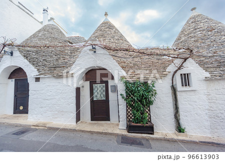 Beautiful town of Alberobello with Trulli houses among green plants and flowers, Apulia region, Southern Italy. 96613903