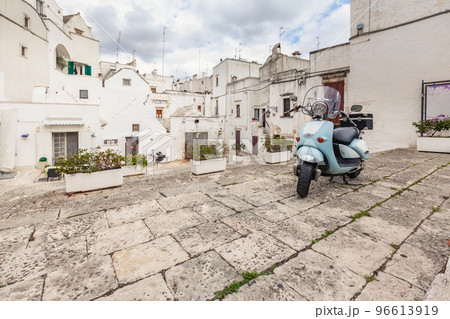 View of the old town of Martina Franca. Classic blue moped on the background of an anient buildings. View of the old town of Martina Franca. Classic blue moped on the background of an anient buildings. 96613919