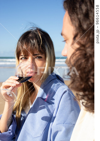 Pretty young woman drinking wine at seashore Pretty young woman drinking wine at seashore 96614558