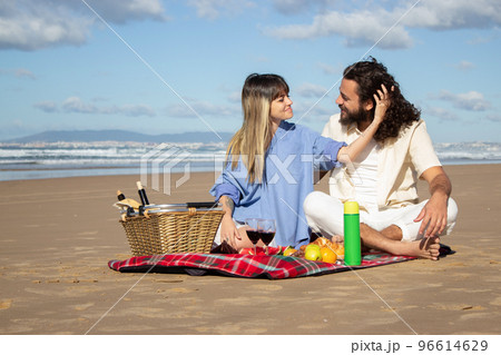 Beautiful young couple having picnic on the beach Beautiful young couple having picnic on the beach 96614629