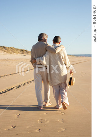 Senior couple walking barefoot on the beach 96614687