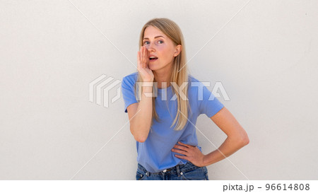 Whispering young woman holding hand near mouth Whispering young woman holding hand near mouth 96614808