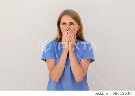 Nervous young woman closing her mouth with hands Nervous young woman closing her mouth with hands 96615030