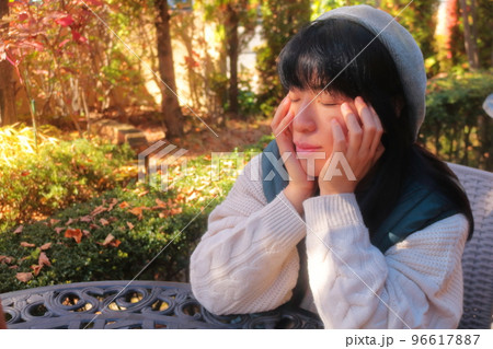 秋の木漏れ日浴びながら物思いにふける女性 96617887