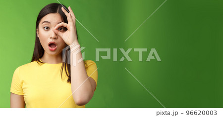 Amazed speechless cute asian young girl drop jaw astonished, look through ok circle sign, drop jaw speechless, impressed look camera, check out incredible promo, stand green background Amazed speechless cute asian young girl drop jaw astonished, look through ok circle sign, drop jaw speechless, impressed look camera, check out incredible promo, stand green background 96620003