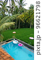 A small private pool in the back of the house, surrounded by a green lawn 96621798