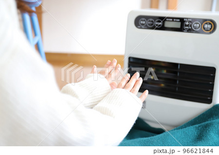ファンヒーターで暖まる女性 96621844