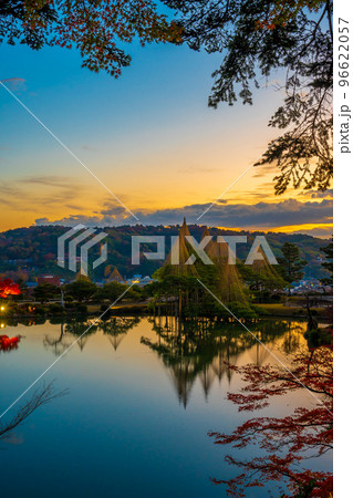 冬の風物詩雪吊りと紅葉が兼六園の霞ヶ池に美しく反射する早朝の風景｜石川県金沢市 96622057