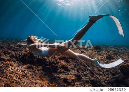 Woman freediver swim with fins over corals. Freediving in blue ocean 96622329