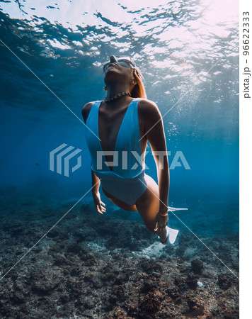 Woman freediver glides over corals. Freediving and beautiful sunlight in blue ocean 96622333