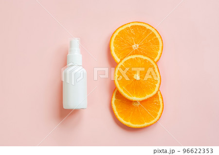 Mockup white cosmetic spray mini travel bottle and three sliced orange on pink background. Body mist, sanitizer, perfume, sunscreen oil with vitamin c. Front view, blank bottle, template. 96622353