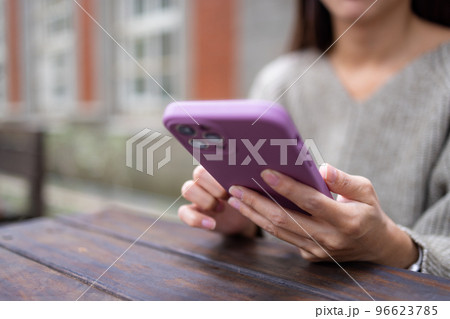 Woman read on cellphone and sit on the table at outdoor 96623785