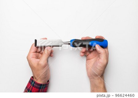 Carpenter's hands Close-up of a man's hands in a plaid shirt on a white background with a chisel, studio shot 96624460
