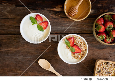 Top view of Strawberry yogurt in a wooden bowl with granola, honey, mint and fresh strawberry on  wooden background. Health food concept. 96627011
