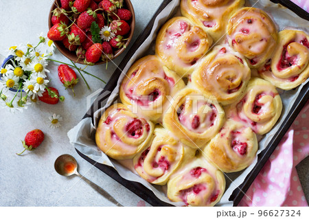 Fresh Homemade Rolls Buns with strawberry with Cream Cheese in glaze for Breakfast on a stone or slate gray background.Top view flat lay background. Fresh Homemade Rolls Buns with strawberry with Cream Cheese in glaze for Breakfast on a stone or slate gray background.Top view flat lay background. 96627324
