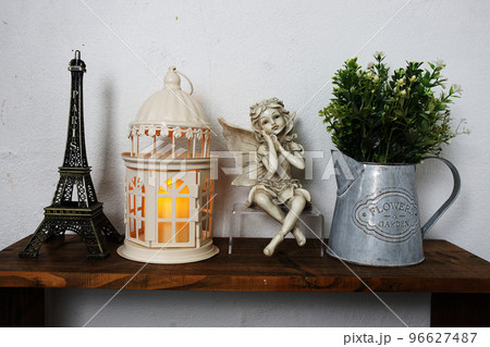 Eiffel tower, white lantern, ceramic doll and artificial plant on wooden shelf Interior home decoration 96627487